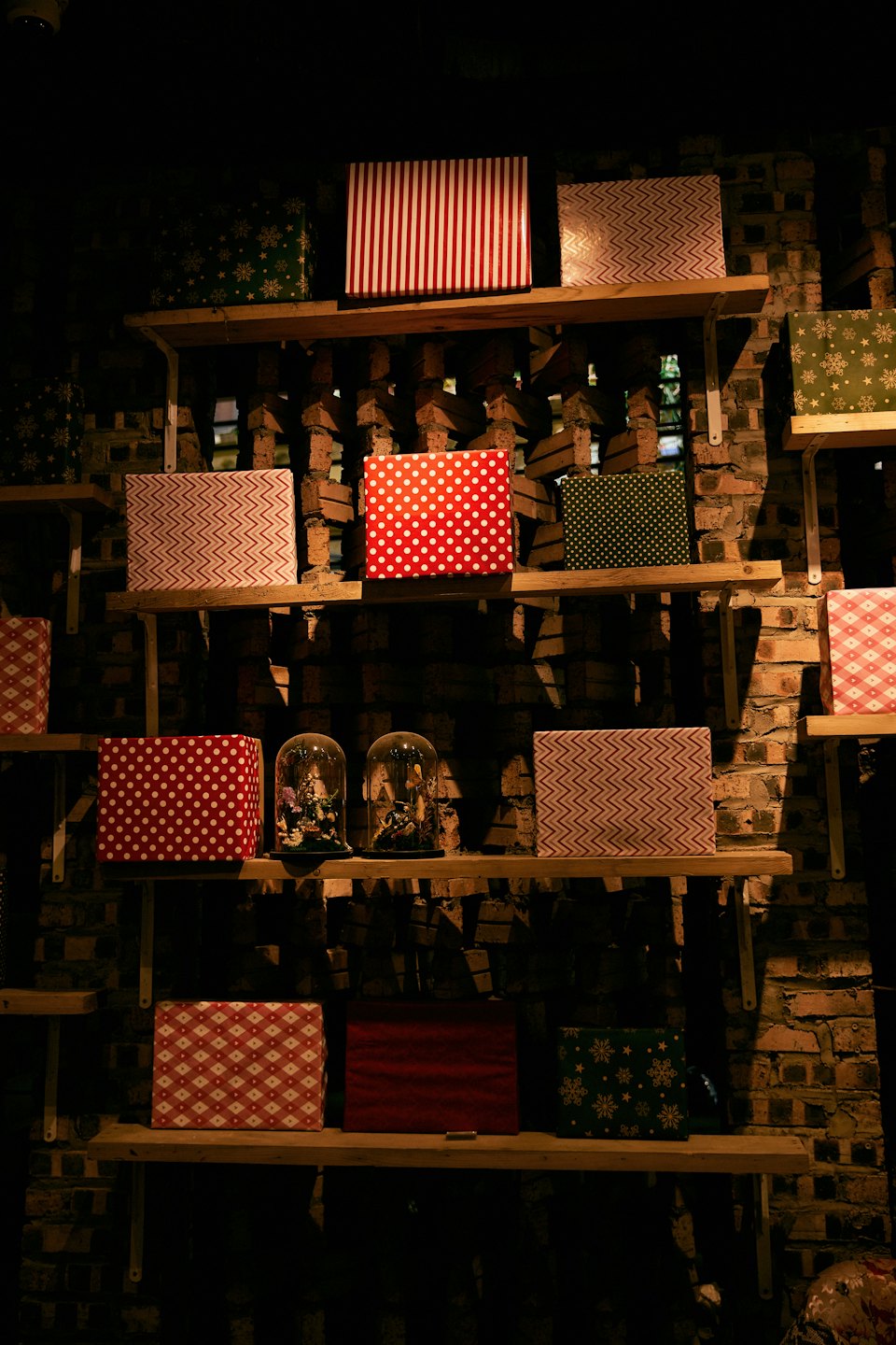 Gift boxes and glass bell jars displayed on wooden shelves.