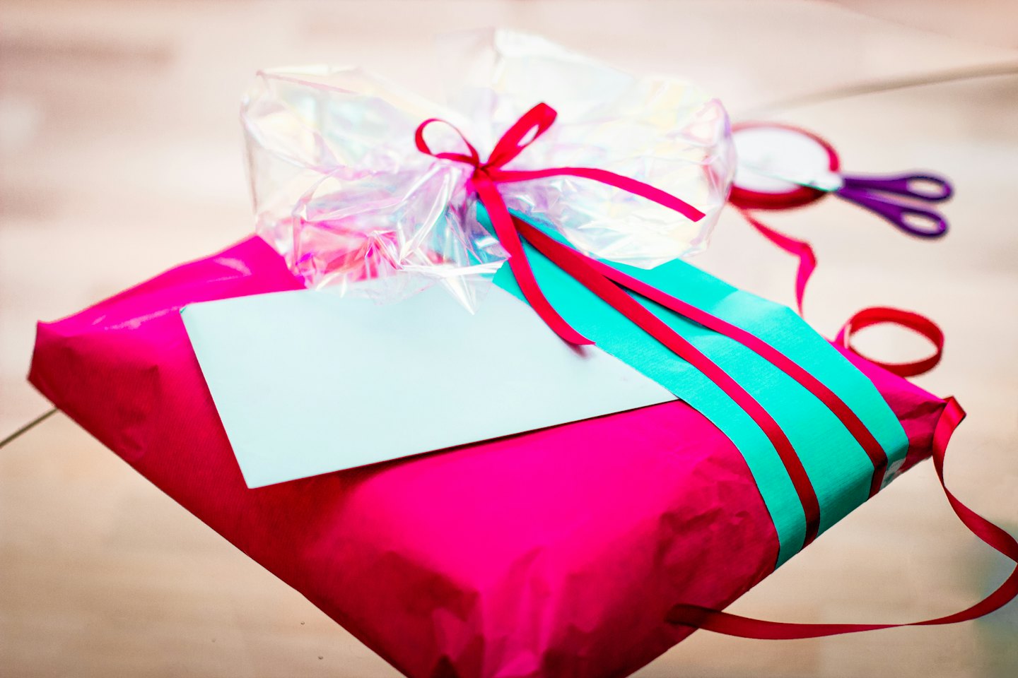 Fuchsia gift box with teal band and red ribbon.